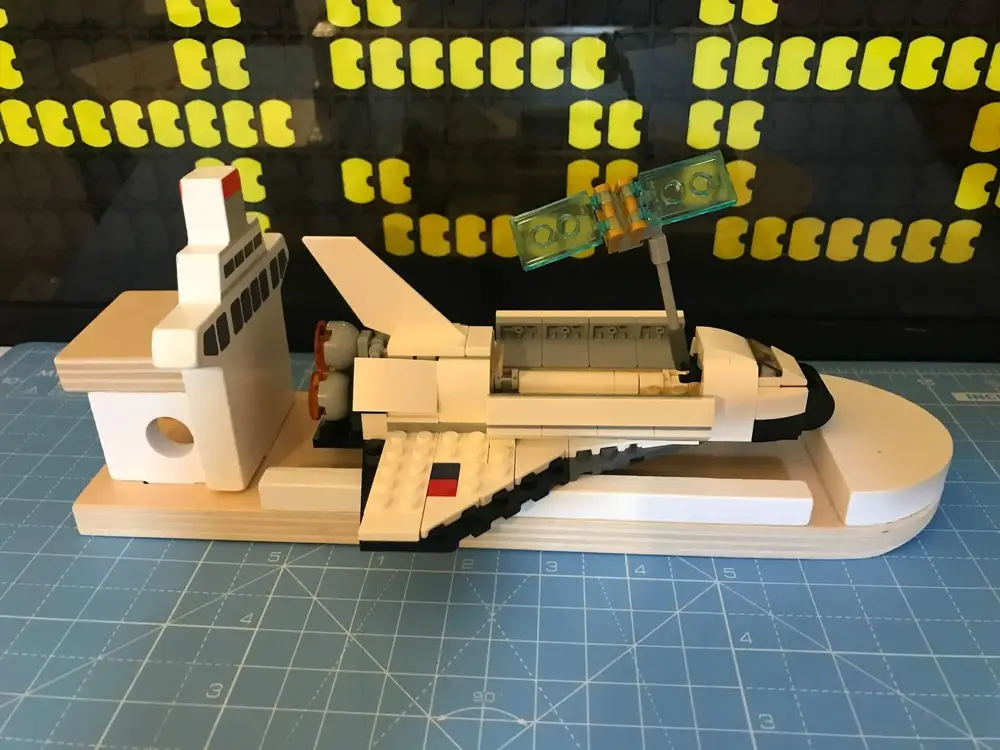 Completed Shuttle on the shipping ship with the payload doors open and satellite raised on the arm.